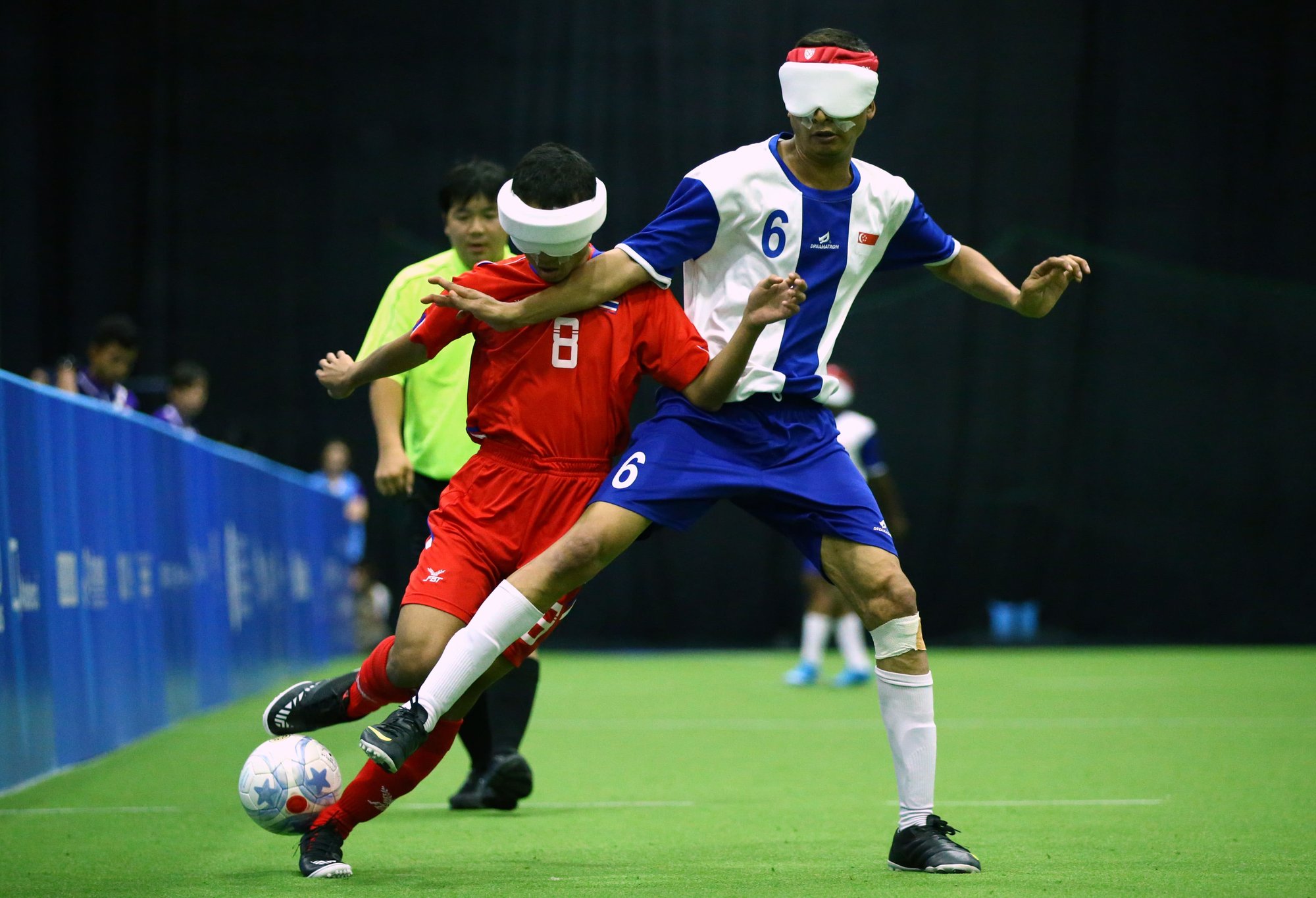 Photo of Blind Football players wearing white shades tussling for the ball