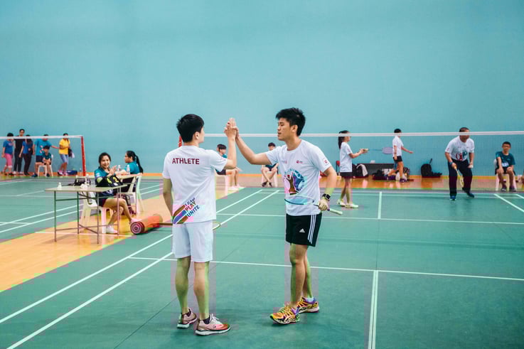 Photo of a special needs badminton player high five his unified partner whithout disability after a game during Play Inclusive
